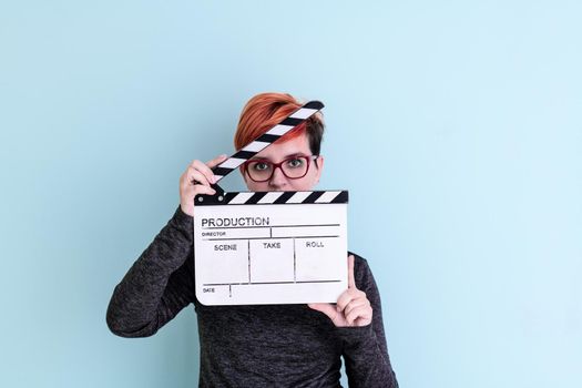 woman holding movie clapper against cyan background