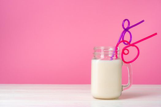 Glassware with fresh milk against pink pastel background