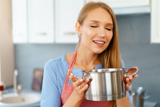Attractive young blonde woman checking cooked food