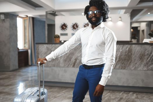 Black businessman with packed luggage standing in hotel lobby