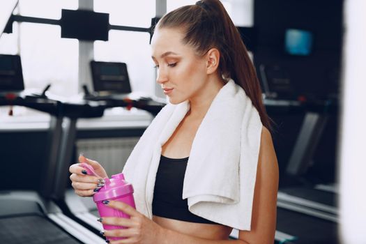 Young sporty woman having a drink in a gym after workout