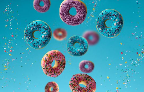 sweet multicolored donuts levitate on a blue background, sugar sprinkles are flying around