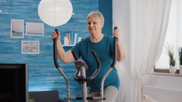 Retired woman training with stationary bicycle at home