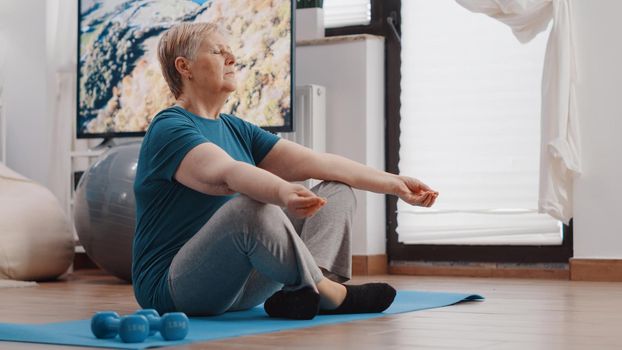 Retired woman meditating after workout training at home