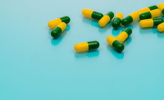 Tramadol pills. Green-yellow capsule pills on blue background. Tramadol is a strong painkiller medicine used to treat moderate to severe pain. Background for tramadol misuse topics. Opioids drug.