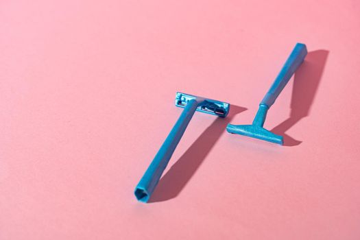 Blue disposable razors on pink paper background