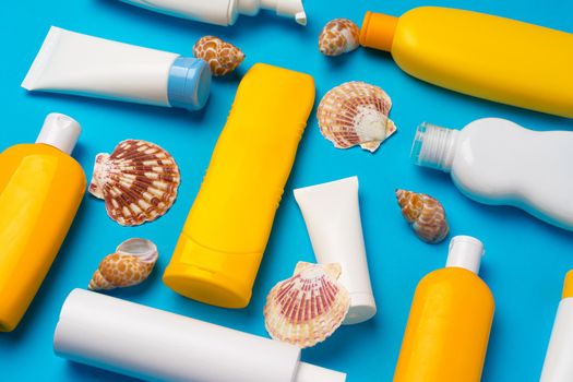 Sunscreen cream bottles with sea shells on blue background