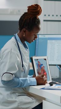 Doctor pointing at cardiology figure on digital tablet