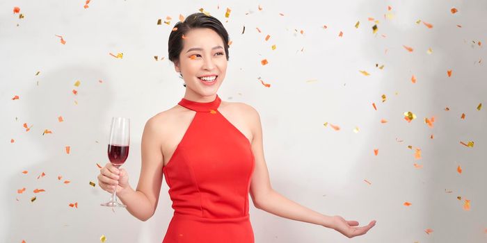 Attractive girl in stylish party attire raising wineglass during event. 