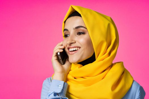 Muslim woman wearing hijab telephone communication technology pink background. High quality photo