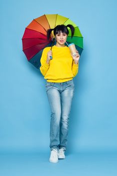 cheerful woman with rainbow colored umbrella posing street style