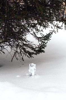 Statuette of an astronaut confidently explores alien planet's surface. Cold planet covered with snow.