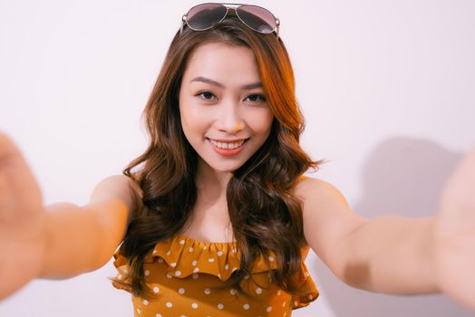 Young woman standing isolated on pastel background taking selfie photo on smartphone posing to camera smiling toothy close-up