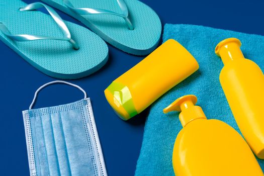 Suntan products in yellow bottles with beach towel and flip-flops