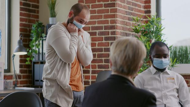 Man with face mask having desperate reaction in front of people at aa group meeting