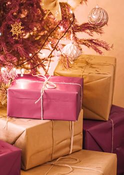 Christmas holiday delivery and sustainable gifts concept. Pink gift boxes wrapped in eco-friendly packaging with recycled paper under decorated xmas tree