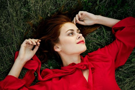 woman in red dress lies on the grass address fashion summer