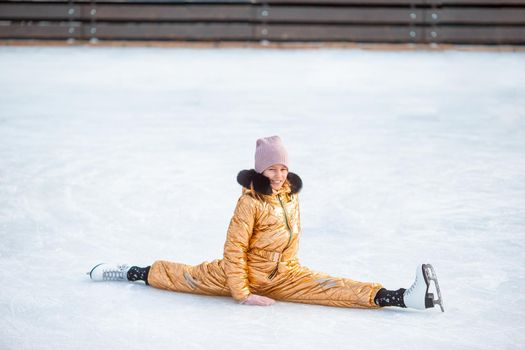 Little adorable girl sitting on ice with skates after fall