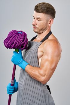 man in apron with mop in hand posing housework