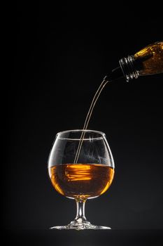 Whisky pouring into a glass on black background