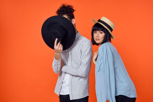 man and woman in hats posing fashion orange background