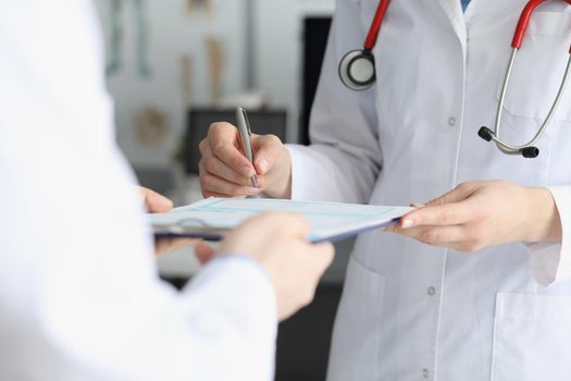Doctor in medical gown put sign on clipboard with prescription paper