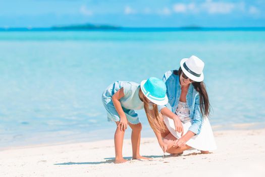 Young beautiful mother and her adorable little daughter on tropical beach