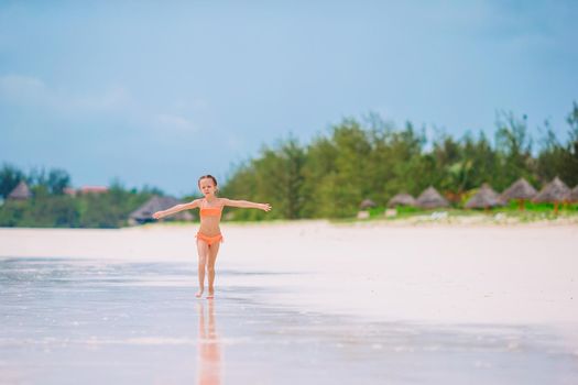 Happy little girl walking at beach during caribbean vacation