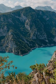 The concept of eco-tourism and active recreation. National Park. Mountain Emerald lake in the wooded mountains. Sunny day in autumn