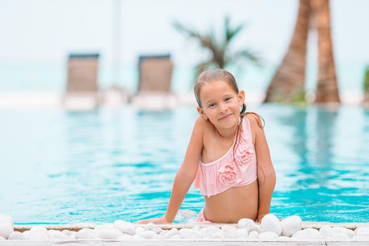 Adorable little girl swimming at outdoor swimming pool