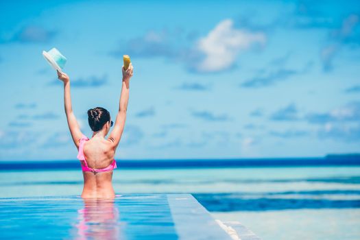 Young beautiful woman enjoying summer vacation in luxury swimming pool