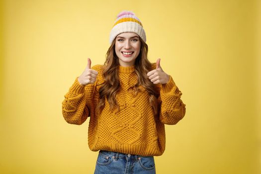 Supportive attractive 20s girl likes your idea show thumbs up positive reply affirmative answer standing pleased smiling recommending promotion satisfied give approval, agree yellow background