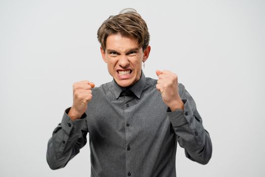 Ready to fight young man defending himself hands in fists in grey shirt with. Angry young adult man showing he is ready for fight isolated on white background