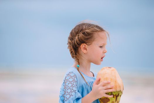 Little adorable girl with big coconut on white sandy beach