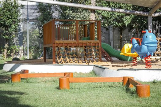 Colorful playground on yard in the park. Rocking horse, Slide and balance beam for children in public park.