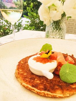 Potato fritter pancake with red caviar, salmon and sour cream in luxury restaurant outdoors in summer