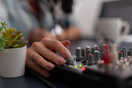 Closeup of hand using volume slider on audio mixing equipment.
