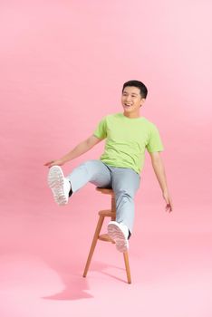 Young handsome man wearing t shirt was sitting in a chair isolated on background