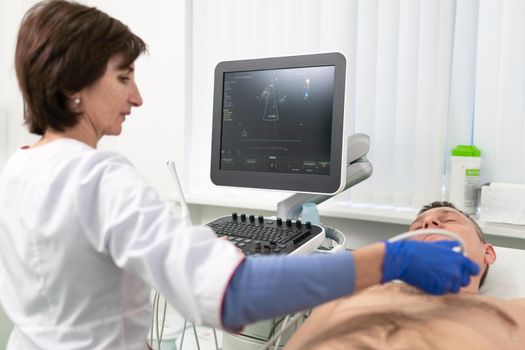 Doctor doing a doppler sonography a male patient in a cardiology clinic. Cardiologist performing an ultrasound examination at the cardiovascular hospital. Echocardiography procedure