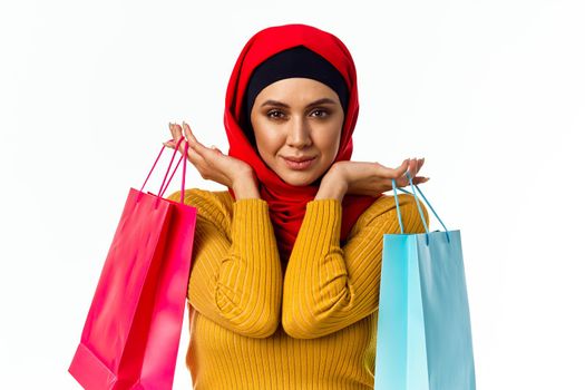 cheerful muslim woman shopping holiday gifts light background