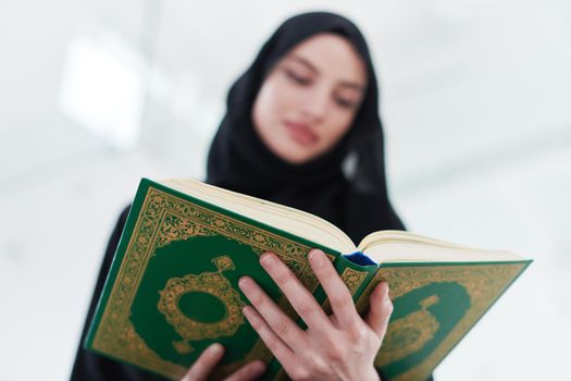 young muslim woman reading Quran at home