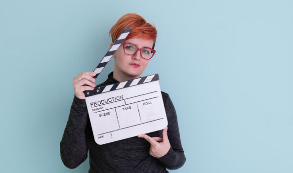 redhead woman holding movie  clapper on cyan background