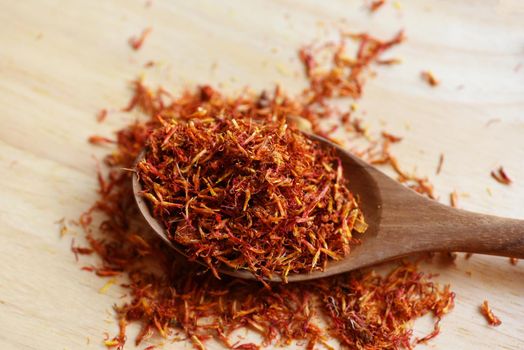 Dried safflower for herbal tea on wood background, dry safflower petals in wooden spoon, Saffron substitute 