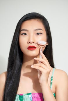 Healthy skin woman using a rose quartz face roller on her flawless skin. 