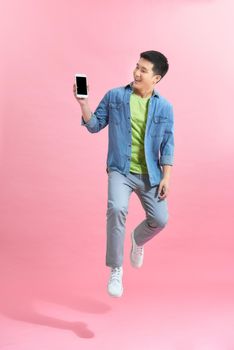 Happy handsome young man showing the smart phone and jumping