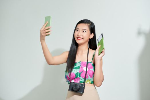 Asian young woman taking a selfie with a passport and airline ticket Before boarding time for a summer trip.