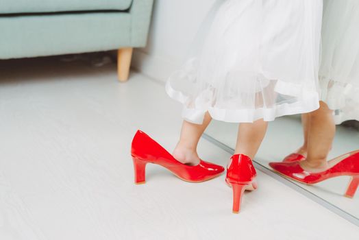 Legs of little girl wearing red high heels