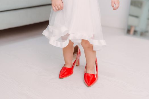 Legs of little girl wearing red high heels