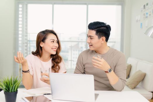 cheerful young male and female laughing while making plans for family budget communicating