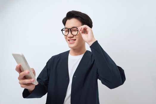 Young handsome Asian man being surprised after reading message from smarrtphone studio short isolated